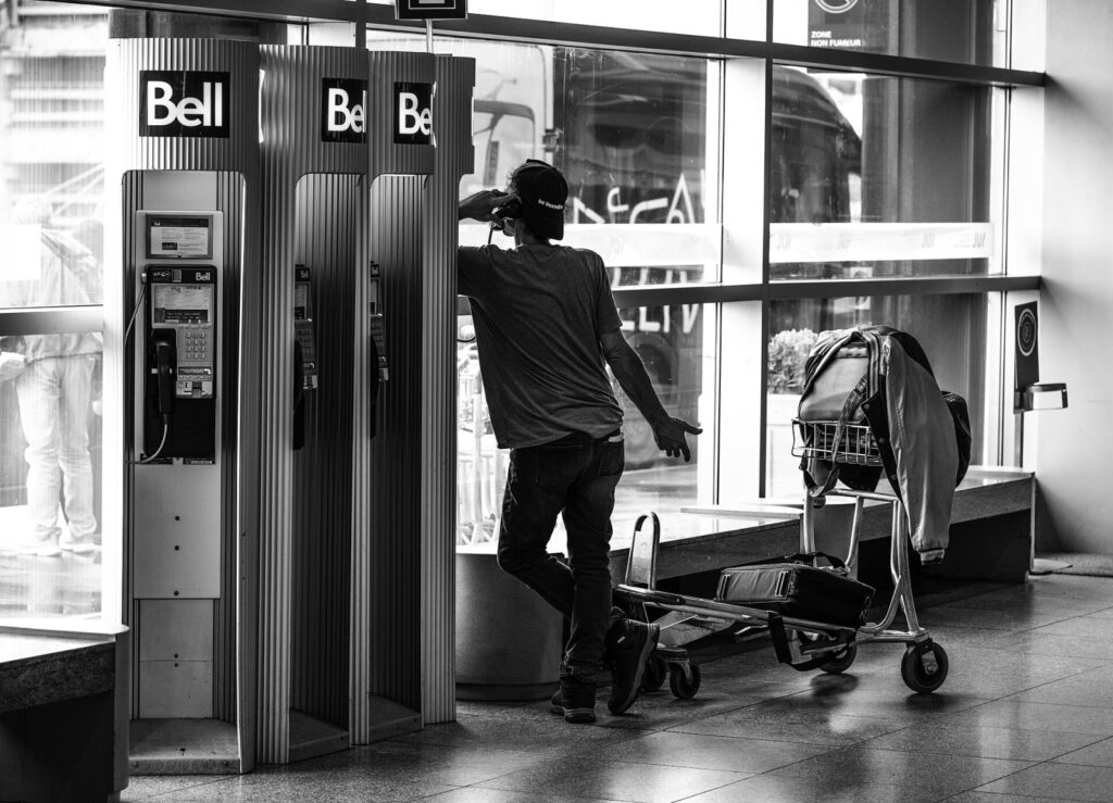Ligar a cobrar dos EUA para o Brasil: o guia definitivo e atualizado Man talking on the phone in Montréal-Pierre Elliott Trudeau International Airport.